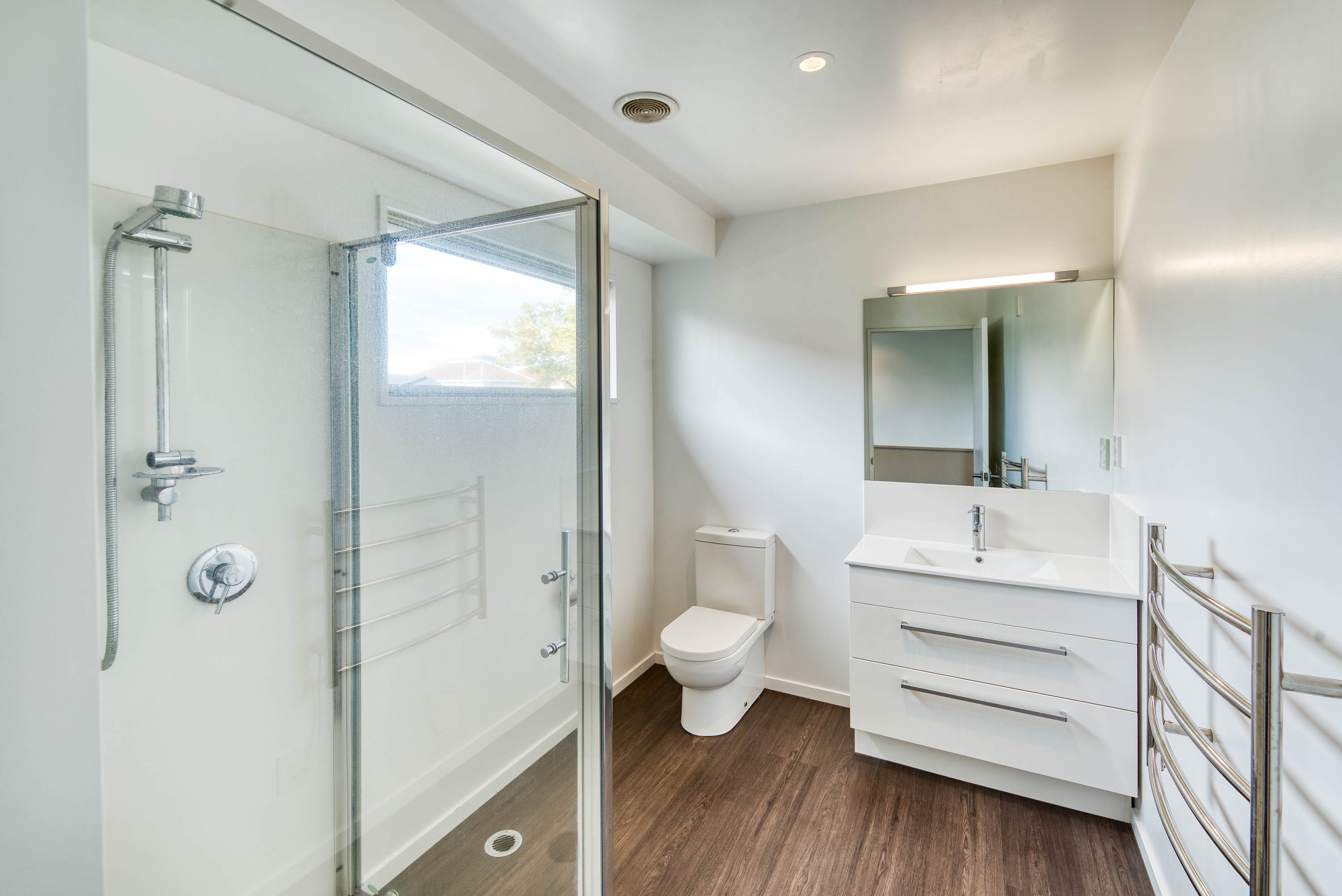 White bathroom with toilet, shower, basin, and vanity cabinet
