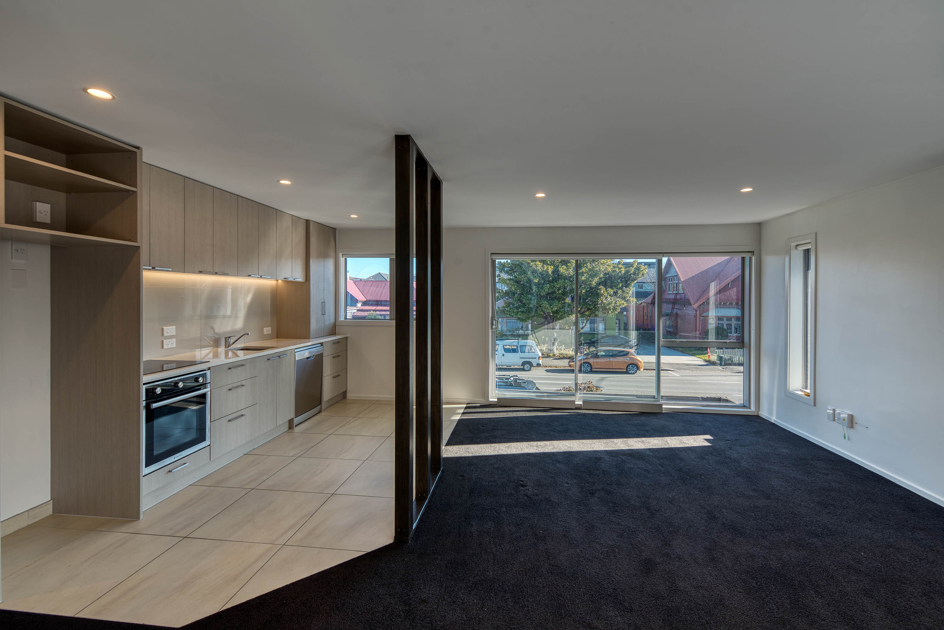 An unfurnished dining room space going to a sliding door and modern kitchen