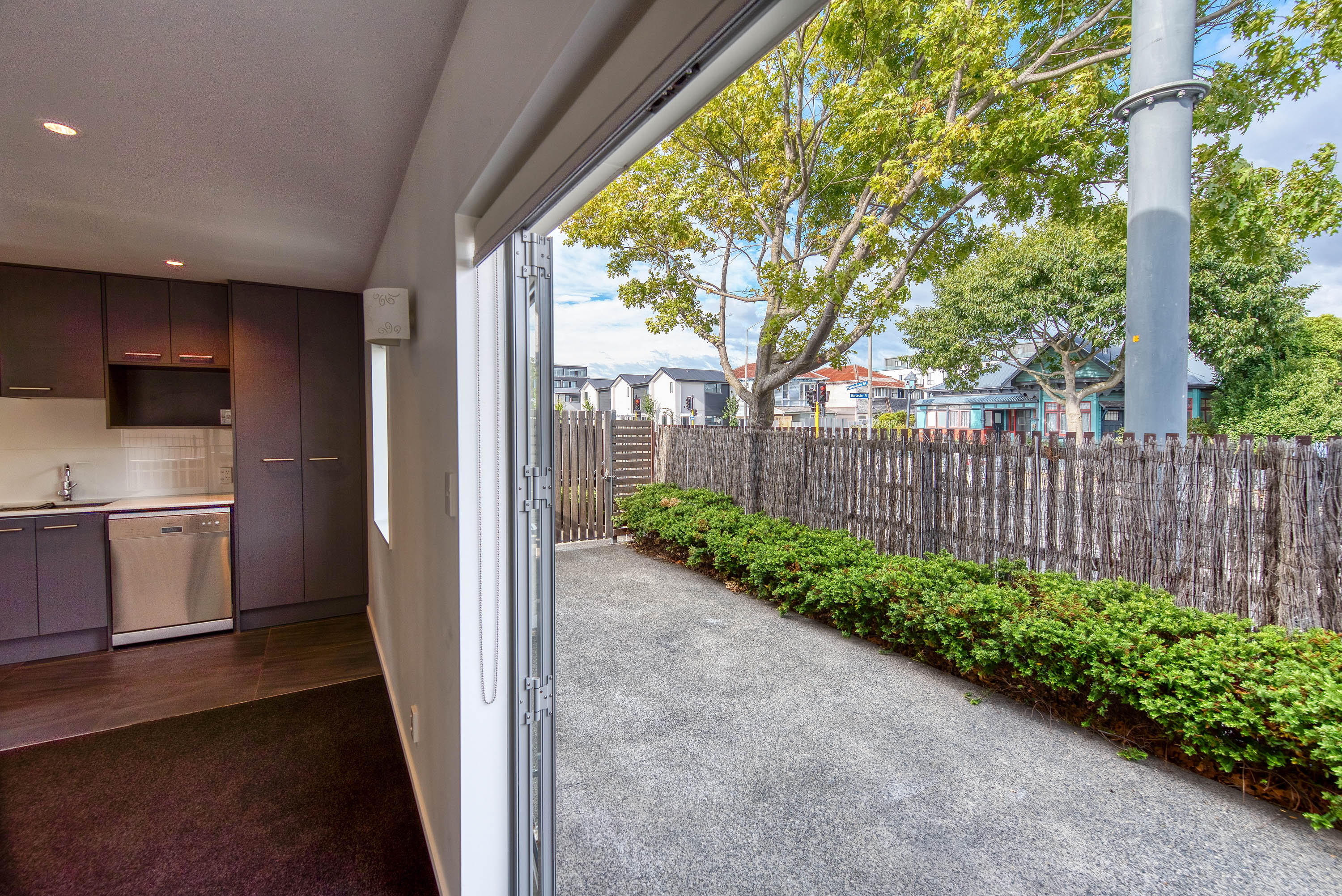 Through a glass sliding door to a courtyard bordered with shrubs